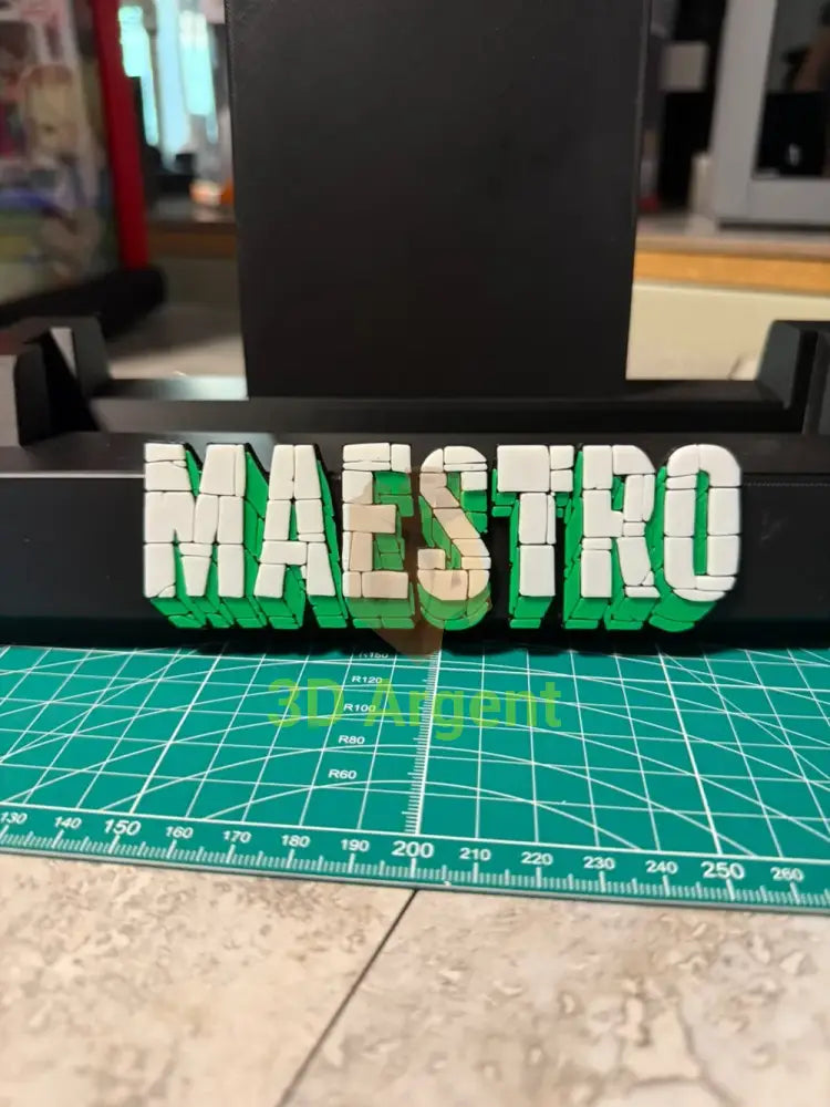 Close-up of the Maestro comic slab display stand showing the layered white and green 3D-effect lettering